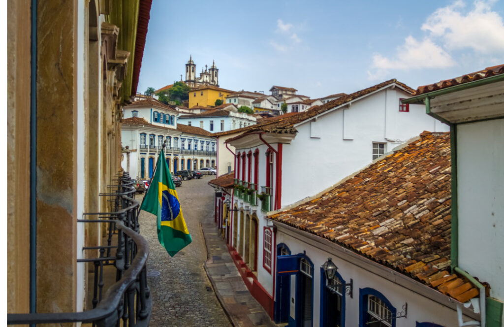 Rua com várias casas e comércio coloridos, sua rua é feita de paralelepípedo, imagem vista de uma sacada na cidade de Ouro Preto-MG