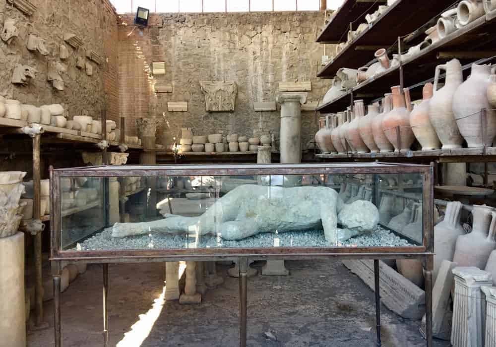 homens feito de gesso a partir de moldes dos corpos que sobraram na época, em uma sala com vários vasos da época da da cidade de pompeia