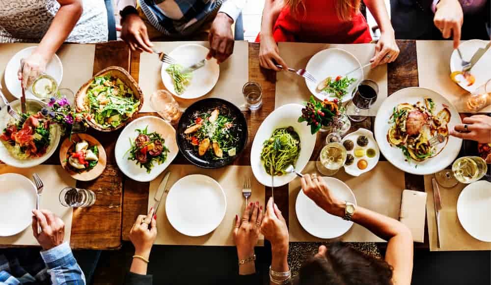 culinária típica do Pará- Varias pessoas se servindo em uma mesa com vários pratos diferentes de comida