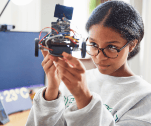 criança adimirando seu projeto de robotica segurando seu robô em suas mãos